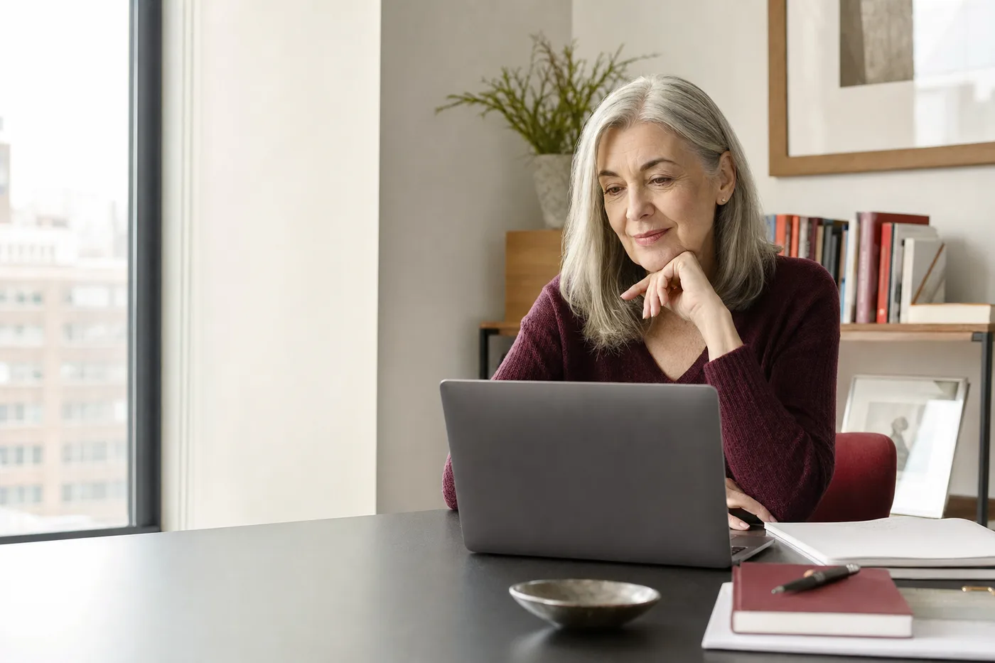 A woman over 50 thoughtfully using online dating at home