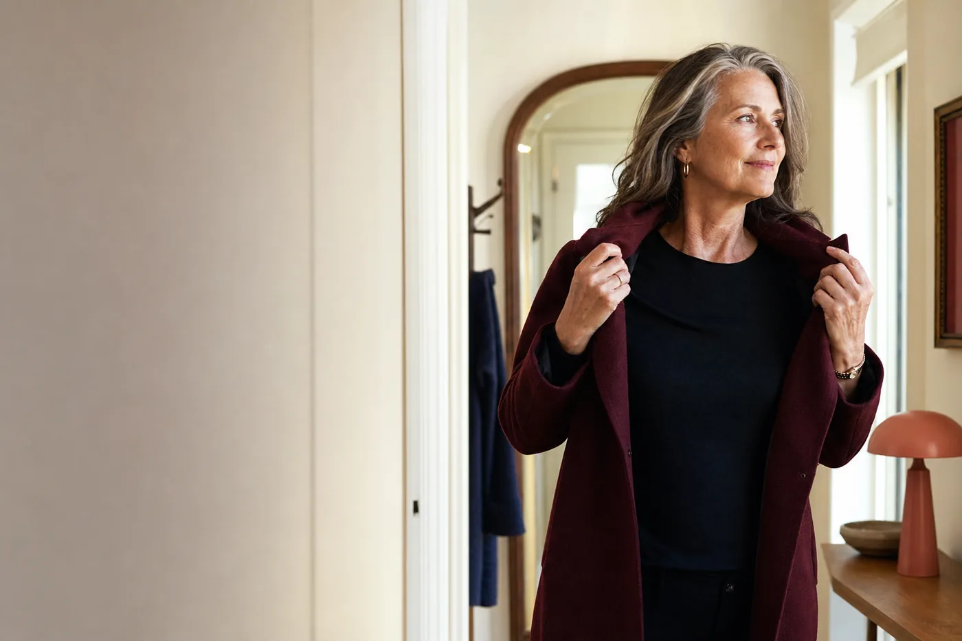 A woman over 50 putting on her coat before going out